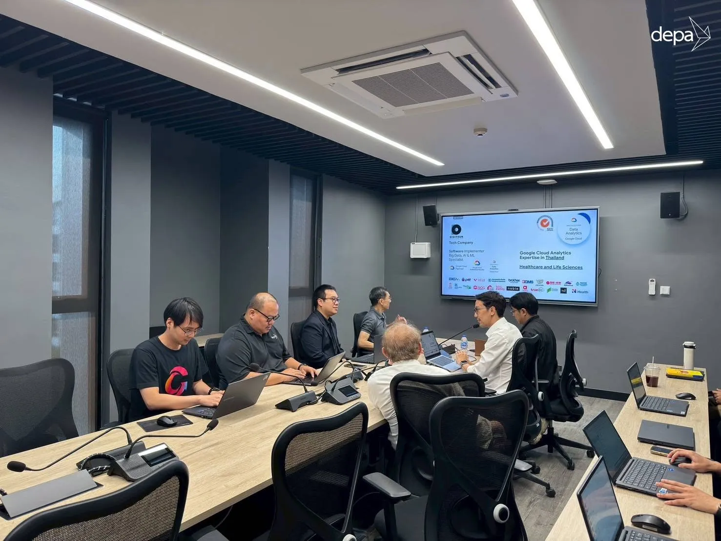 The same meeting room, with a slide headed “Google Cloud Analytics Expertise in Thailand — Healthcare and Life Sciences” above a row of client logos.