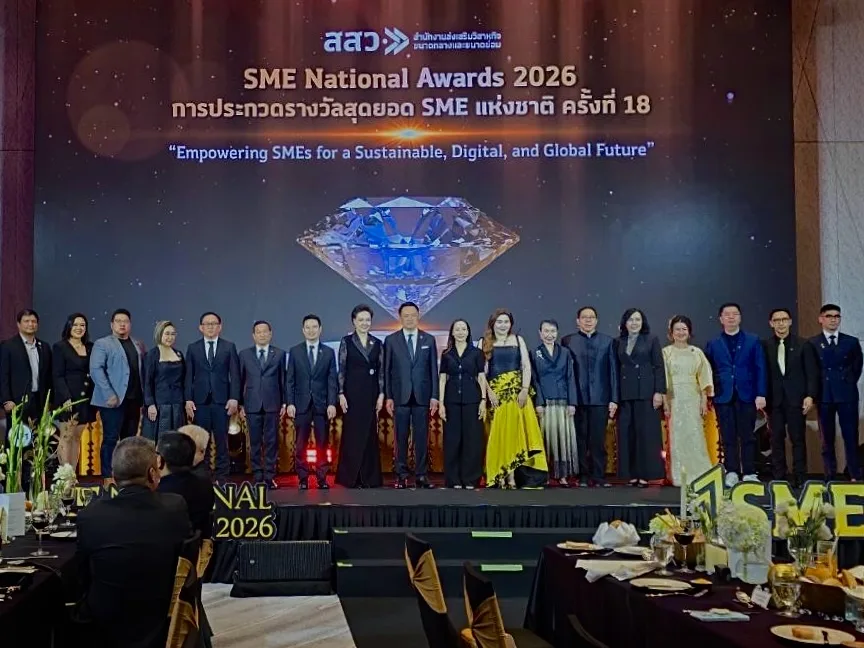 About twenty people standing in a line on stage, in front of a screen reading “SME National Awards 2026 — Empowering SMEs for a Sustainable, Digital, and Global Future”.